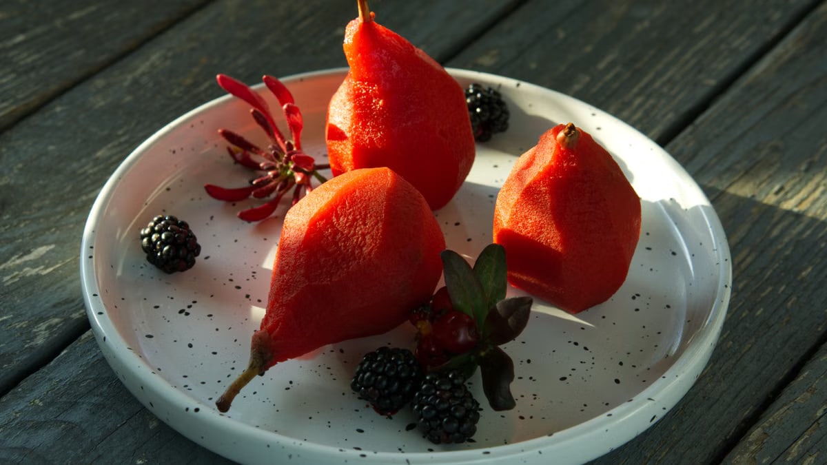 Close-up of poached pears and blackberries on a white plate, perfect healthy dessert.